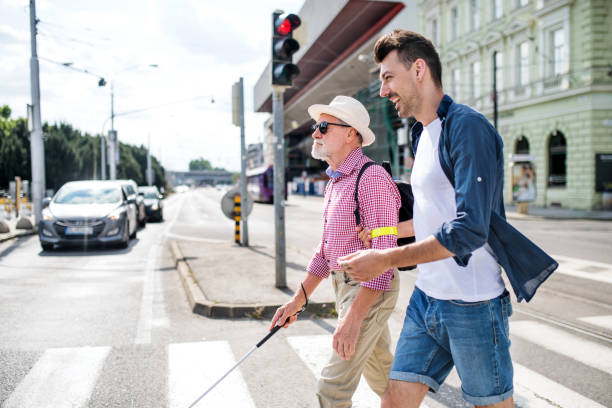 young man helping blind man cross street
